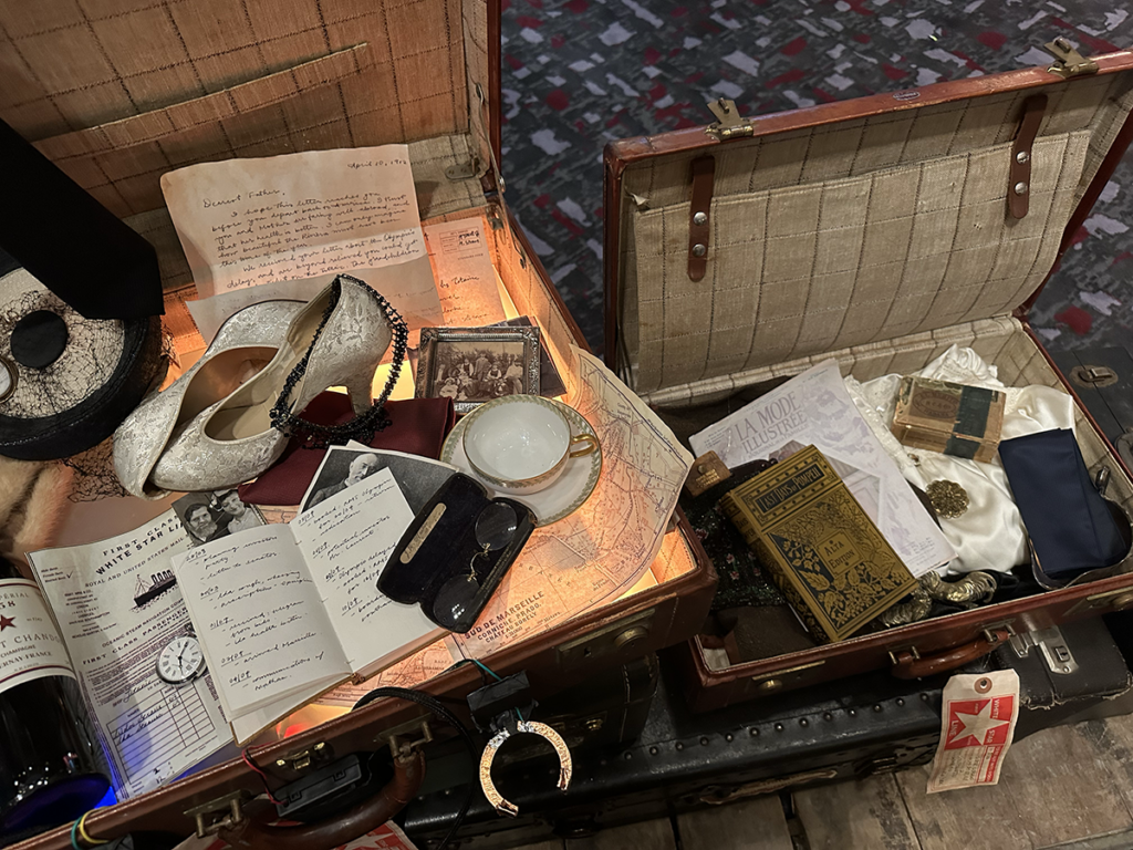 One of the installation’s interactive luggage stations, featuring period-era props 
Credit: Malaya Heflin
